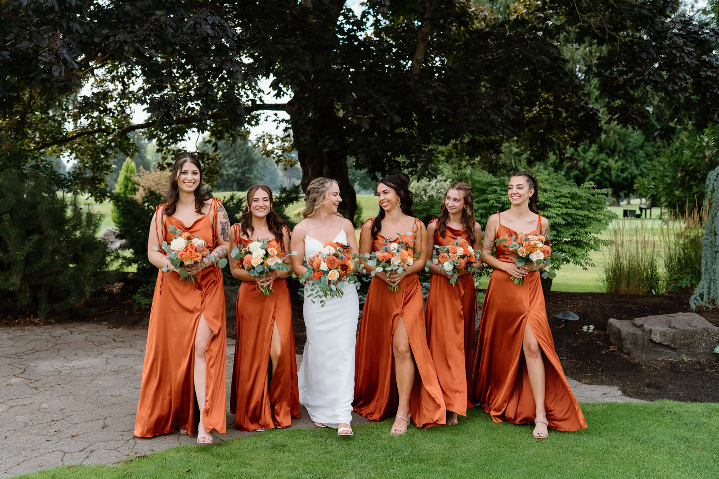 Bridesmaids walking together with their terracotta bouquets and dresses