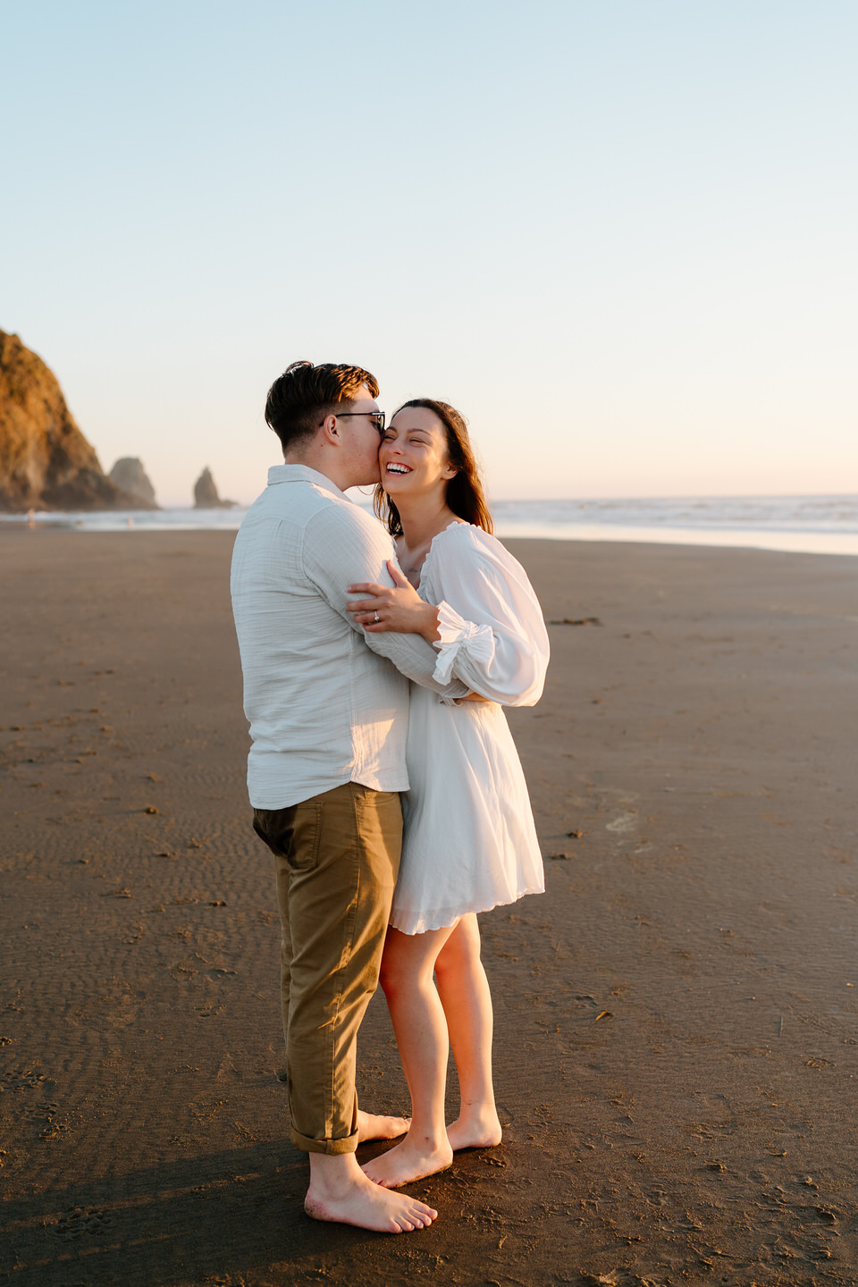 man kissing woman on cheek on the oregon coast at cannon beach