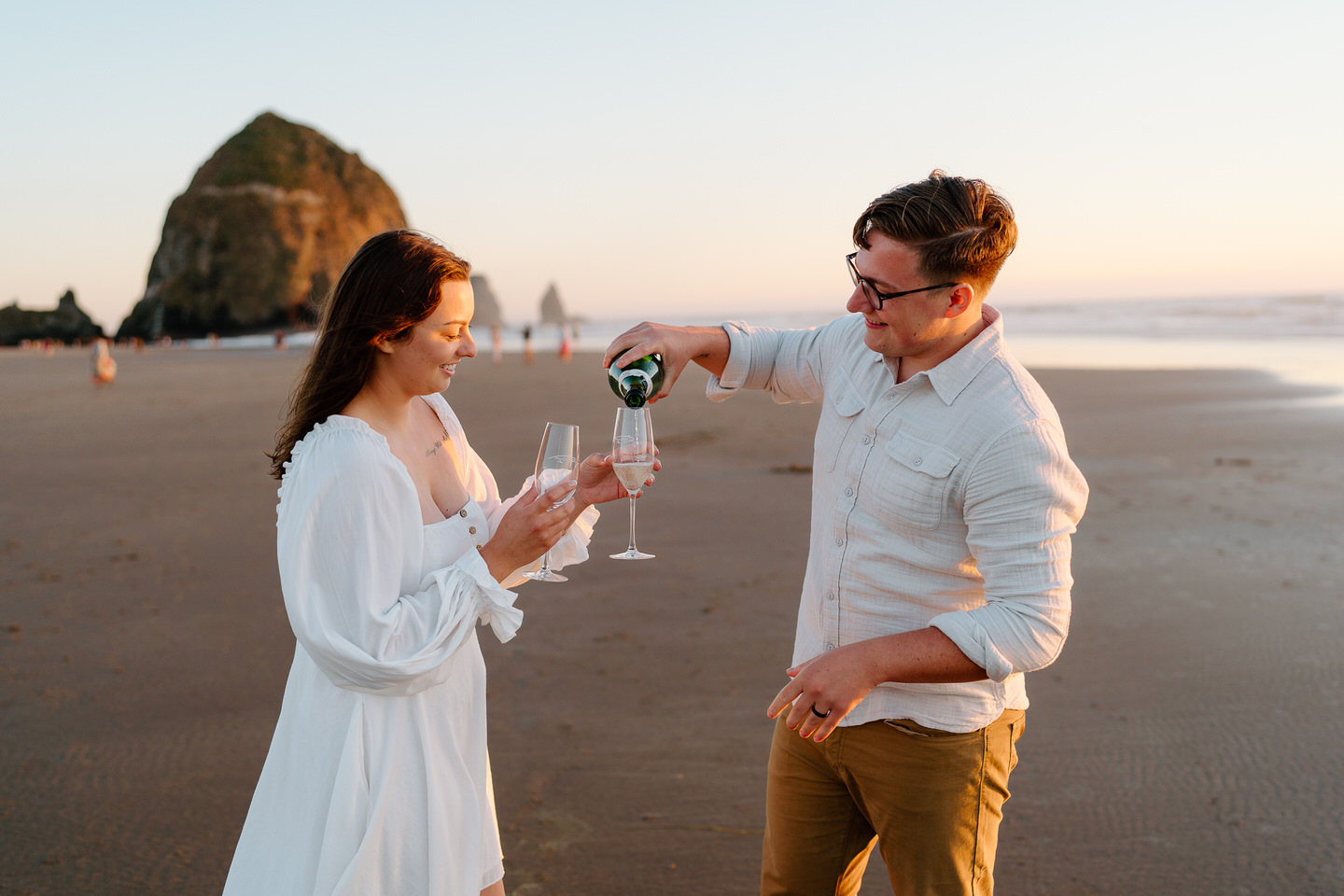 couple pouring champagne into glasses on the coast