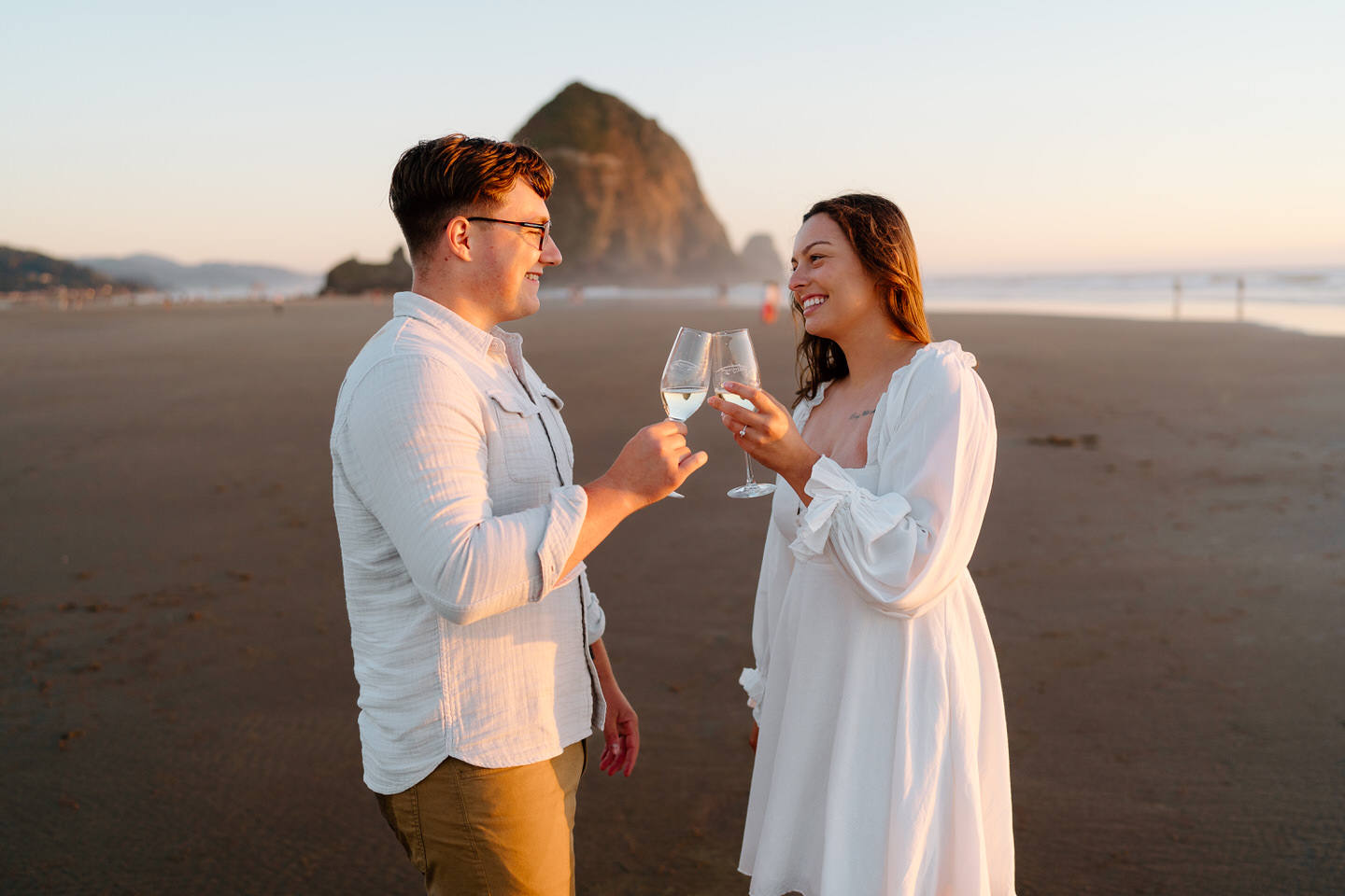 couple toasting to their engagement on the oregon coast