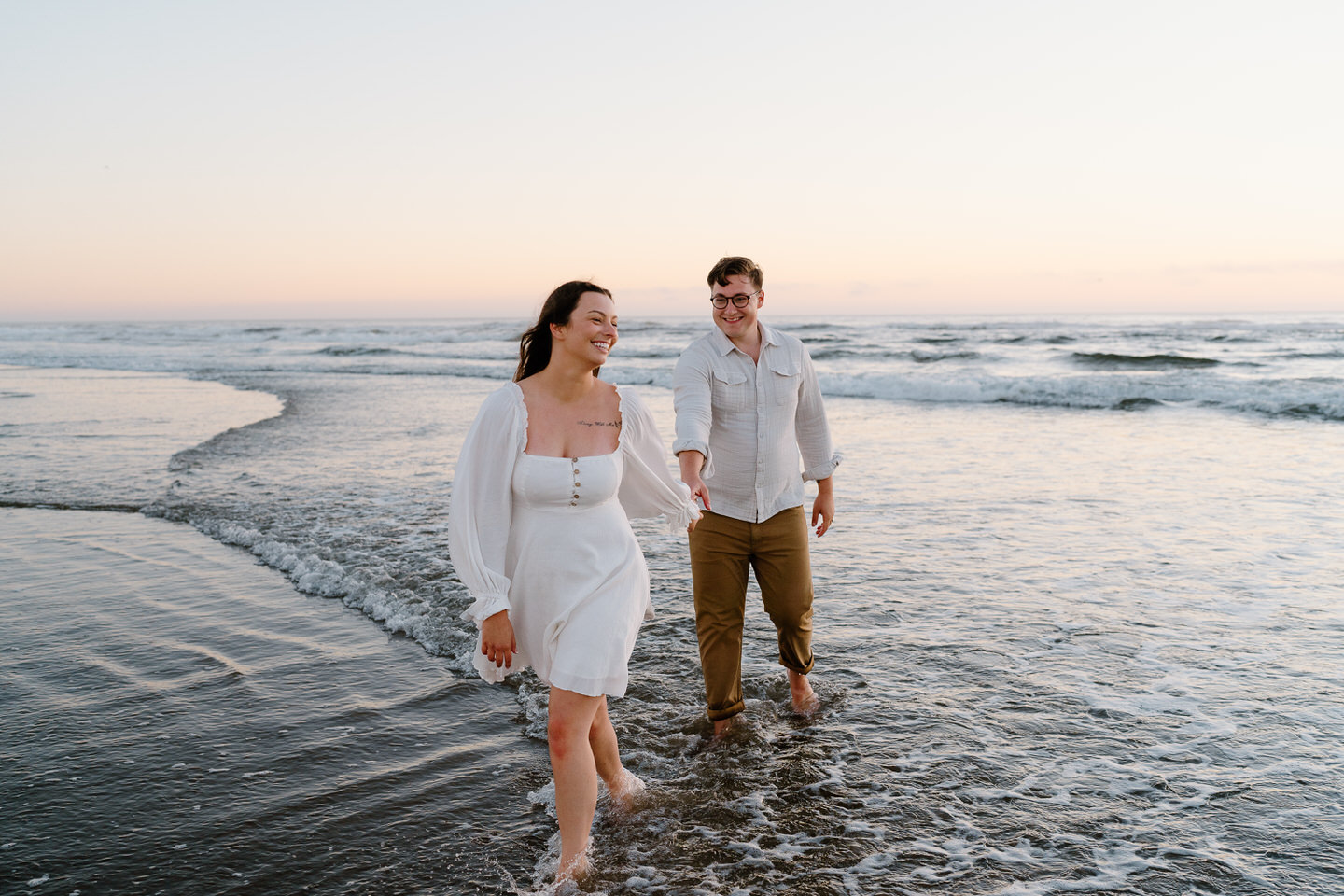 Couple walking barefoot on the oregon coast holding hands for engagement photos