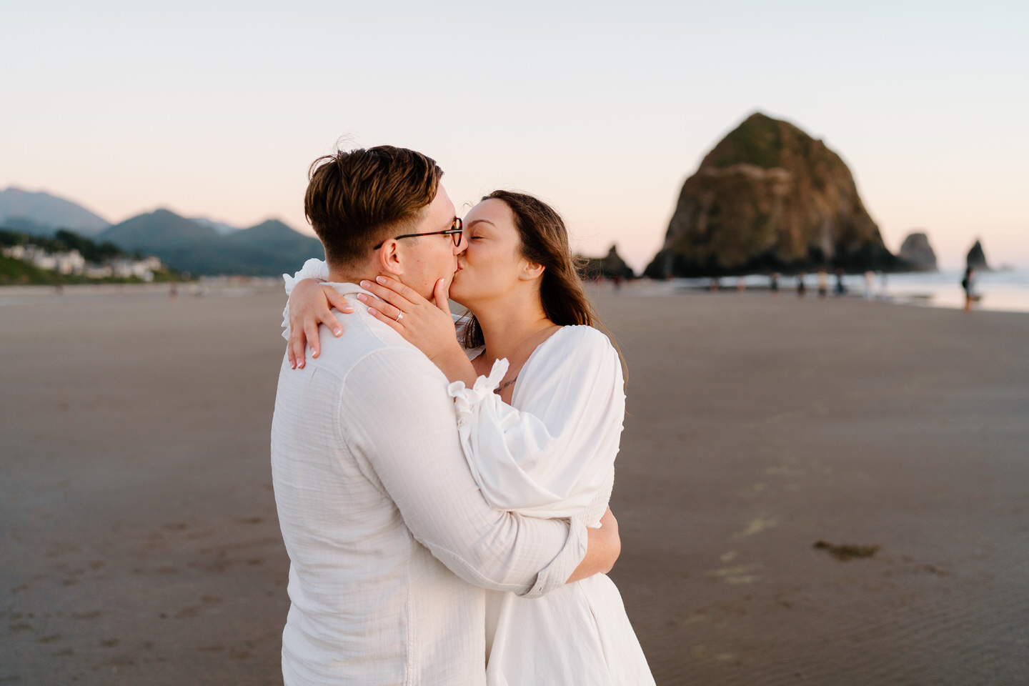couple kissing for oregon coast engagement photos in front of haystack rock