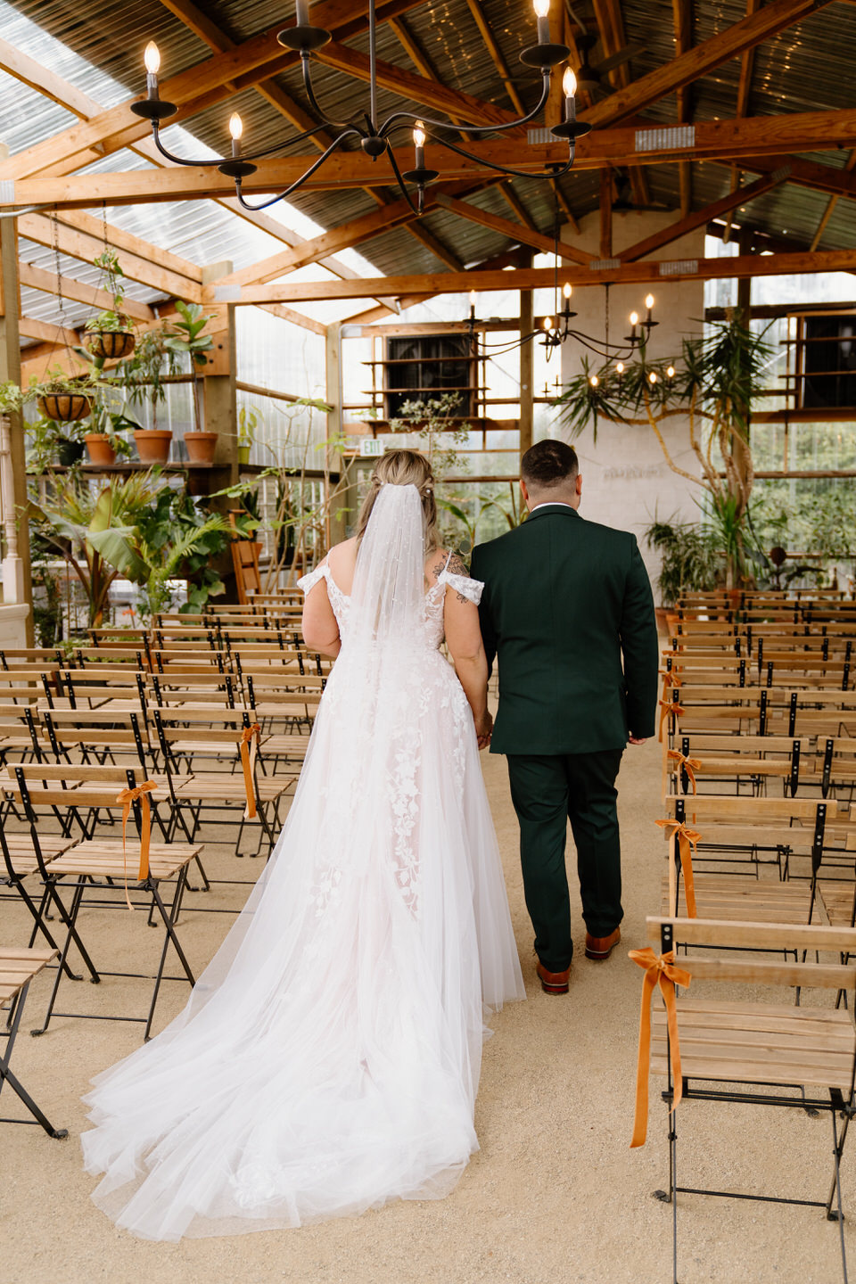Bride and groom walking down aisle in greenhouse