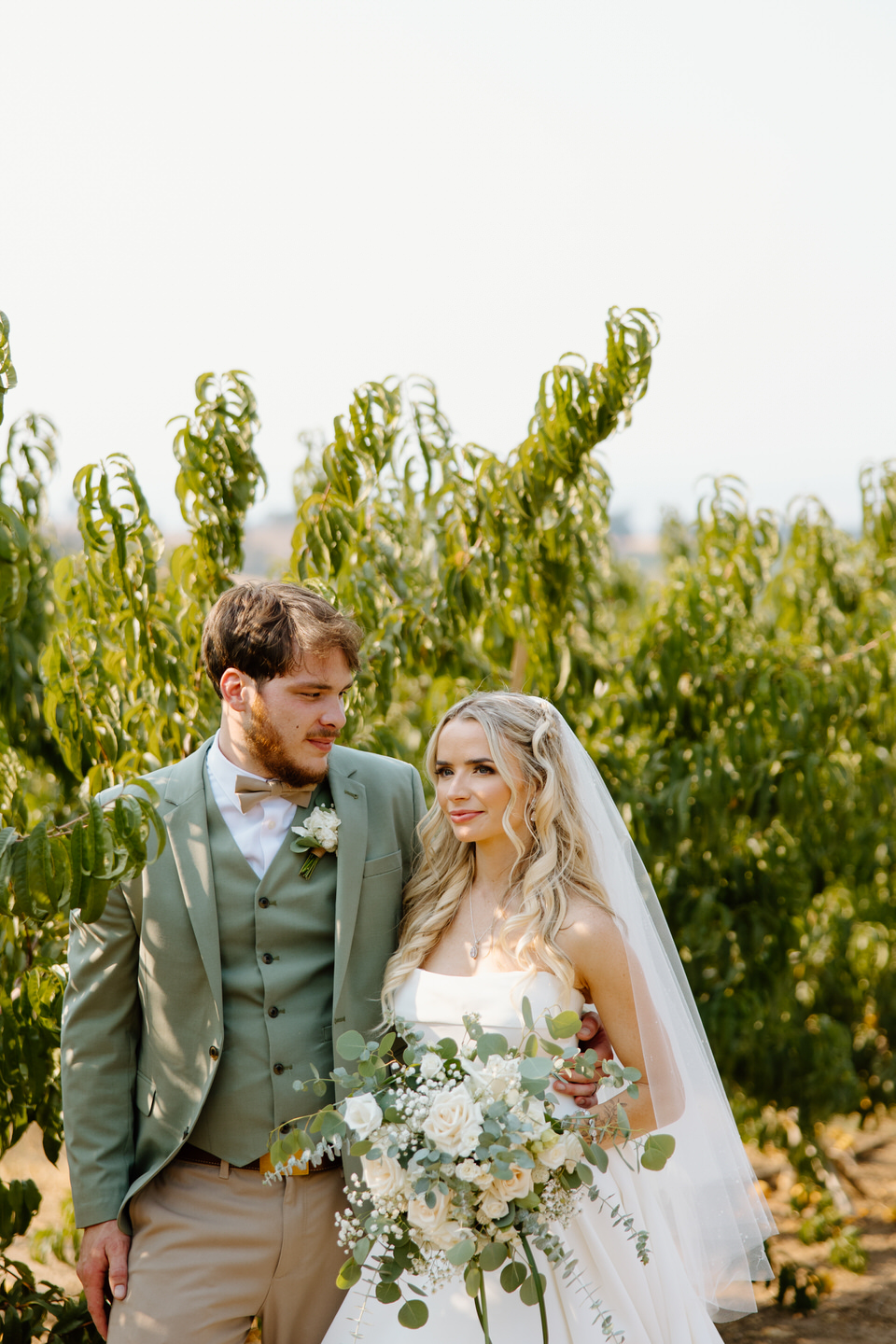 bride and groom in the orchard of their rustic barn wedding venue