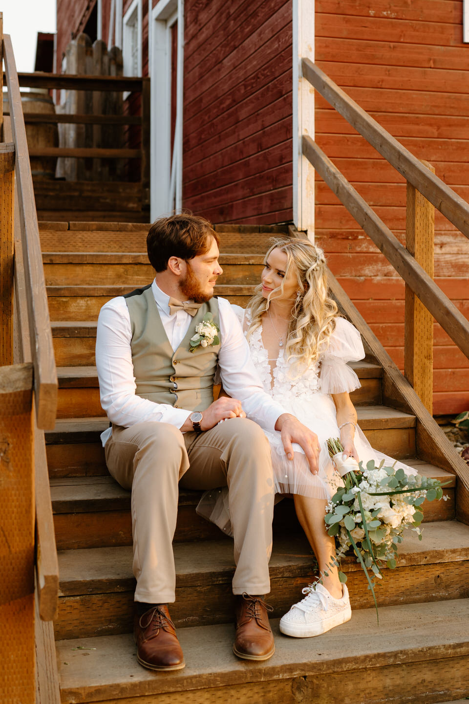 bride and groom sitting on the steps at their rustic barn wedding