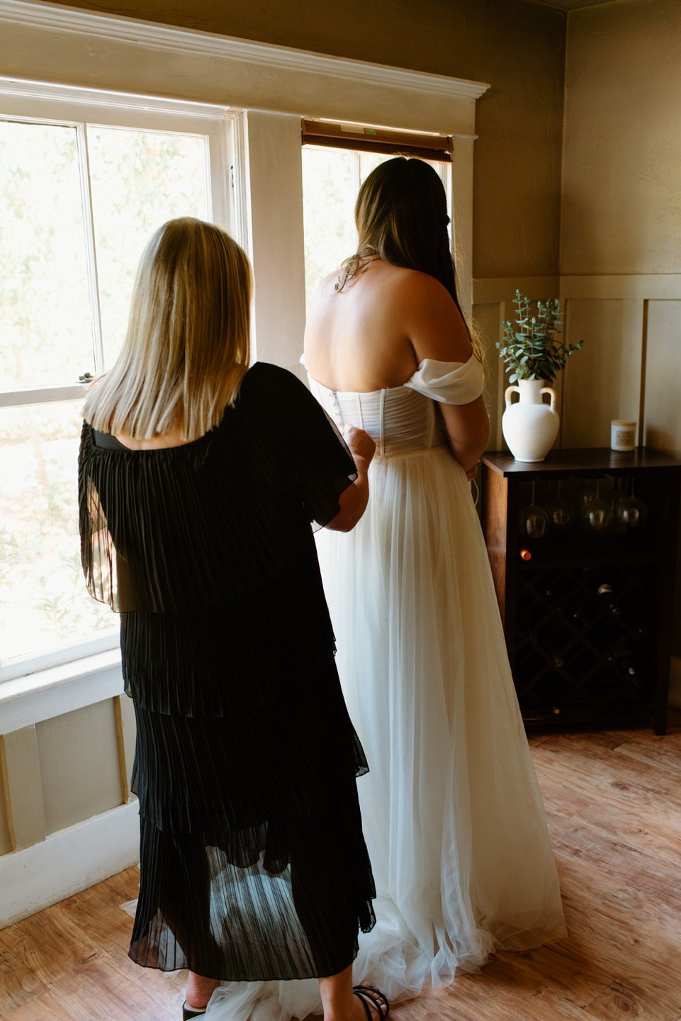 mom zips bride into dress in dining room