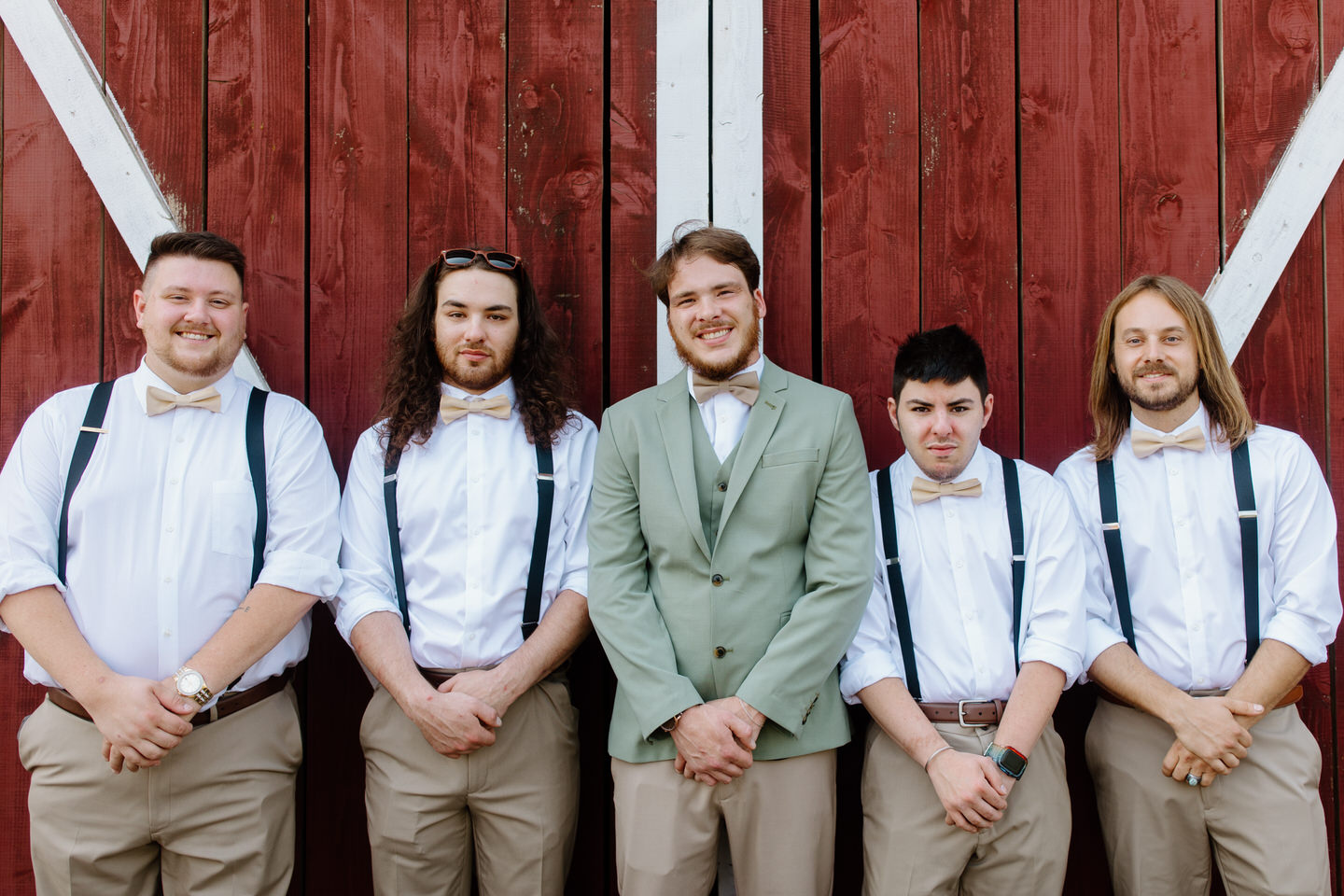 groom and groomsmen in front of red rustic barn for wedding