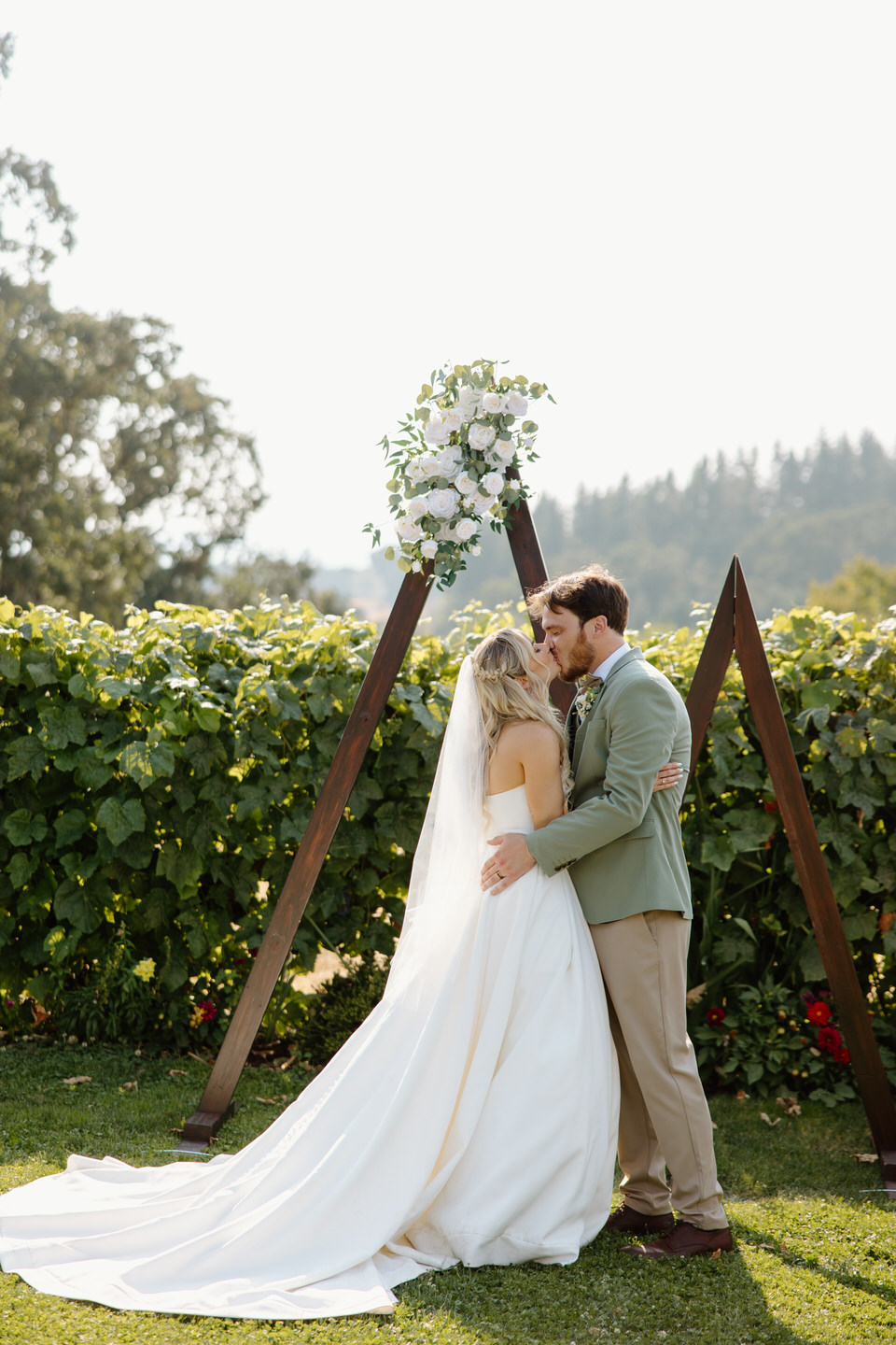 first kiss in the garden vineyard with triangle arch backdrop