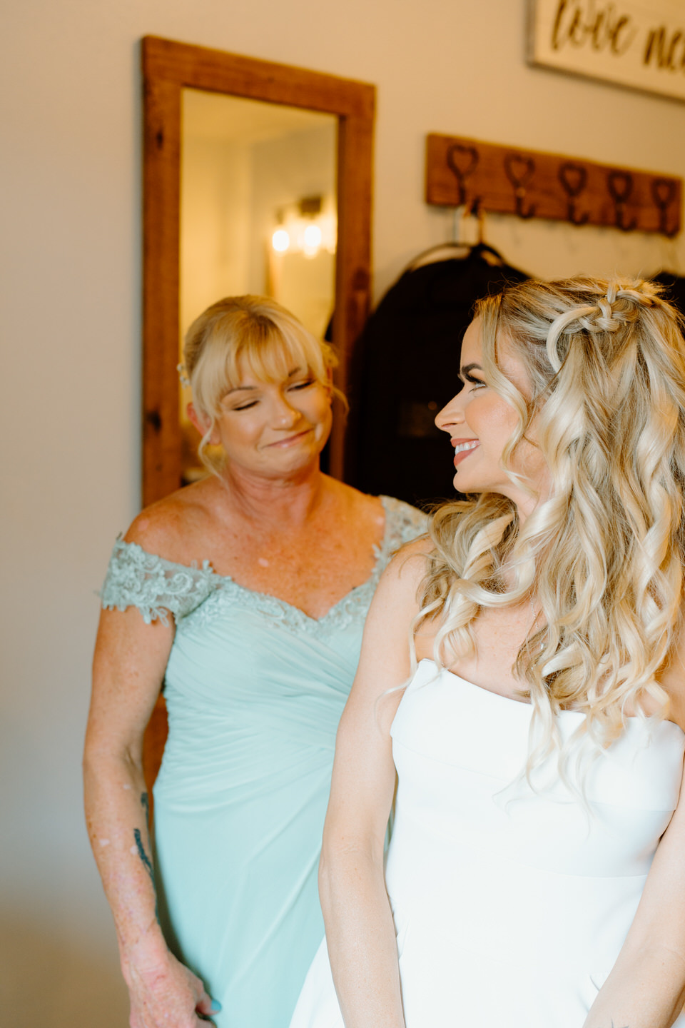bride getting ready and smiling at mother