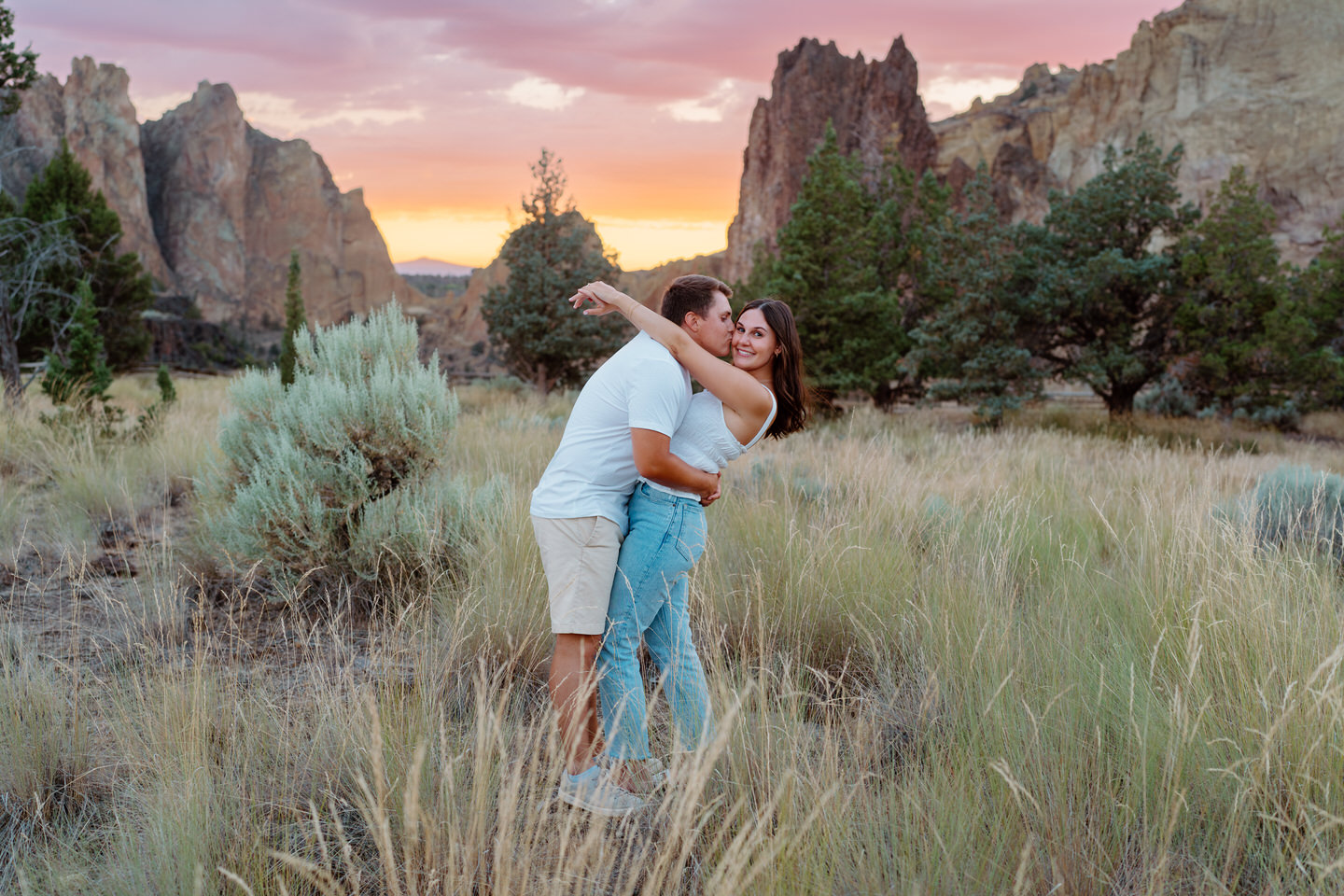 man kissing woman on cheek in front of bright sunset