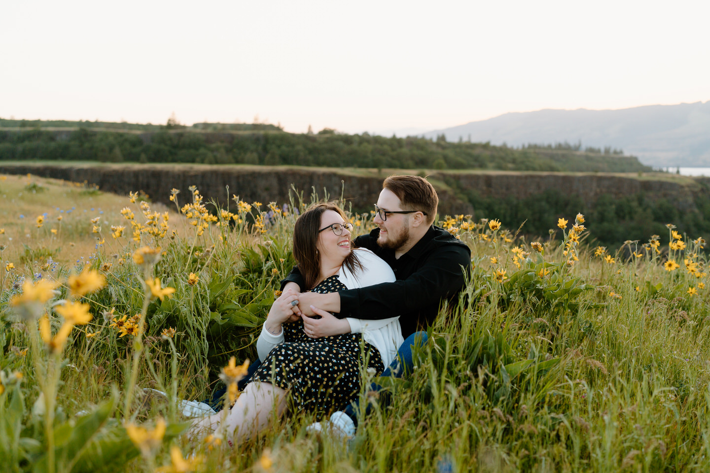 couple sitting in a wildflower patch during columbia gorge wildflower engagement photo shoot