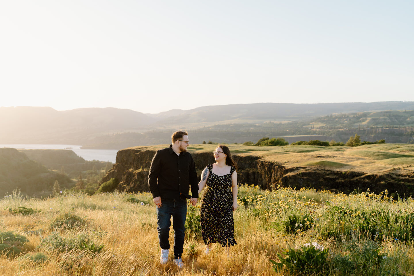 engaged couple walking in wildflower field in columbia gorge