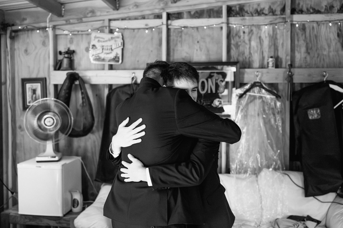 Groom and brother hug in groom's suite at Navarra Gardens while getting ready for wedding.