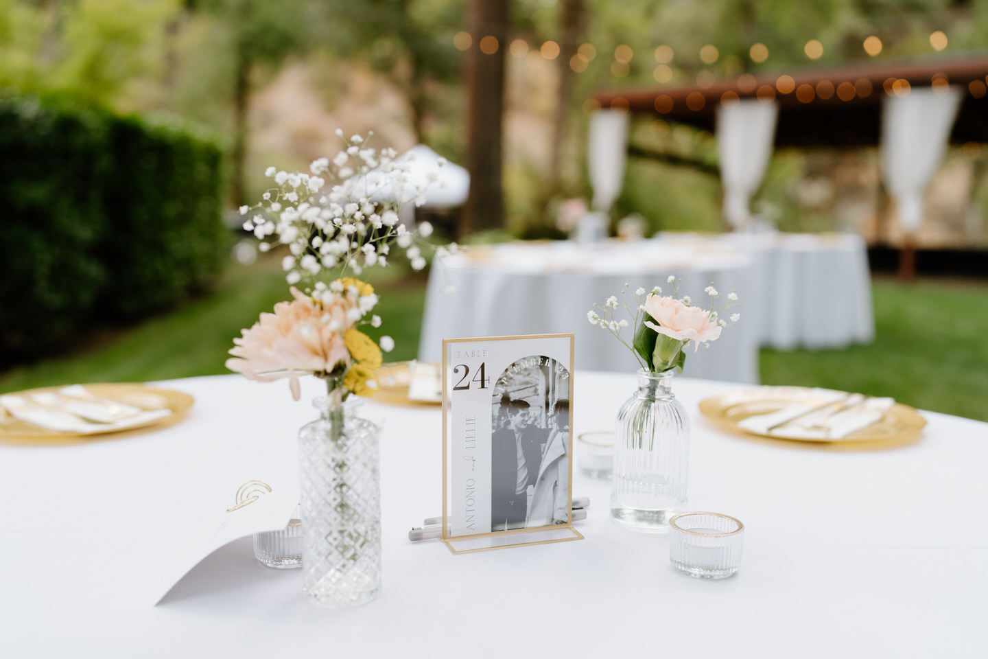 Close up of table decor for a white and gold outdoor wedding reception.