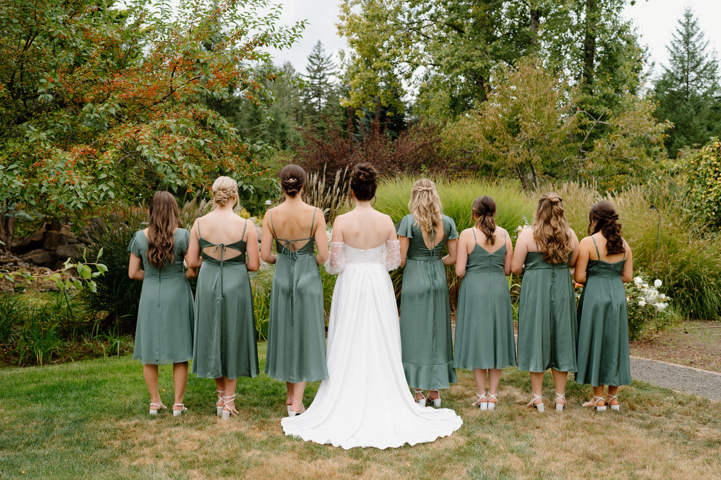 The back of the bride and bridesmaids' dresses. Inspiration for green midi bridesmaids dresses.