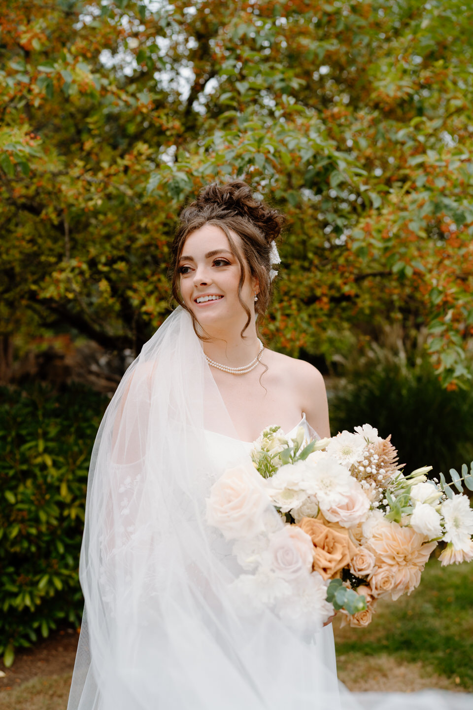 Bride with her veil wrapped around her shoulder at Navarra Gardens.