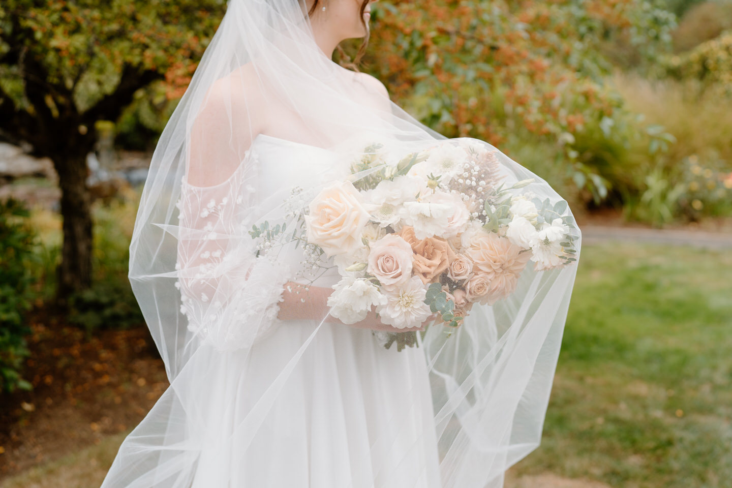 Veil covering bride and her bouquet. The bouquet is made of fall colors.