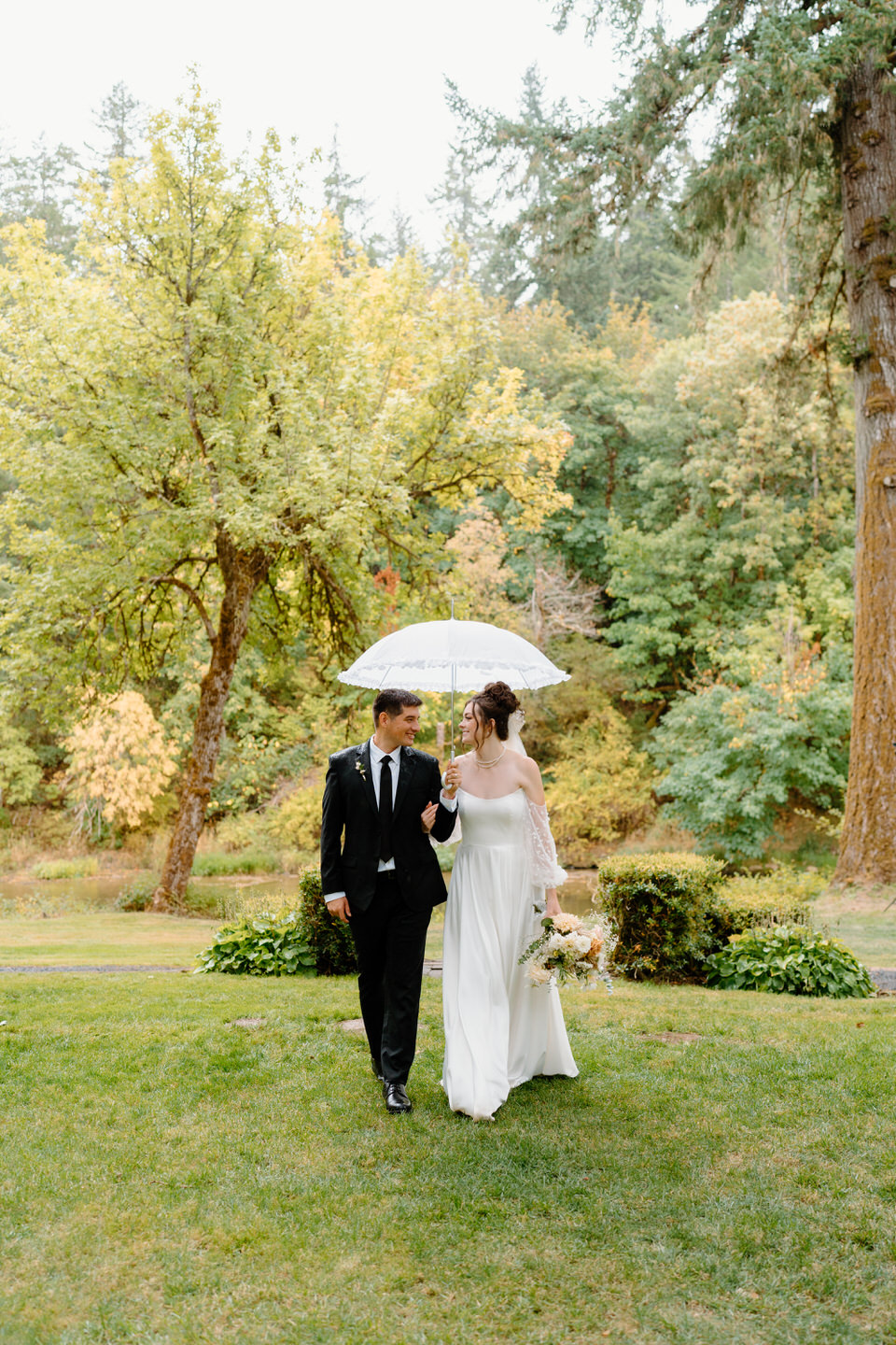 Bride and groom walk together in the rain at Navarra Gardens in Oregon.