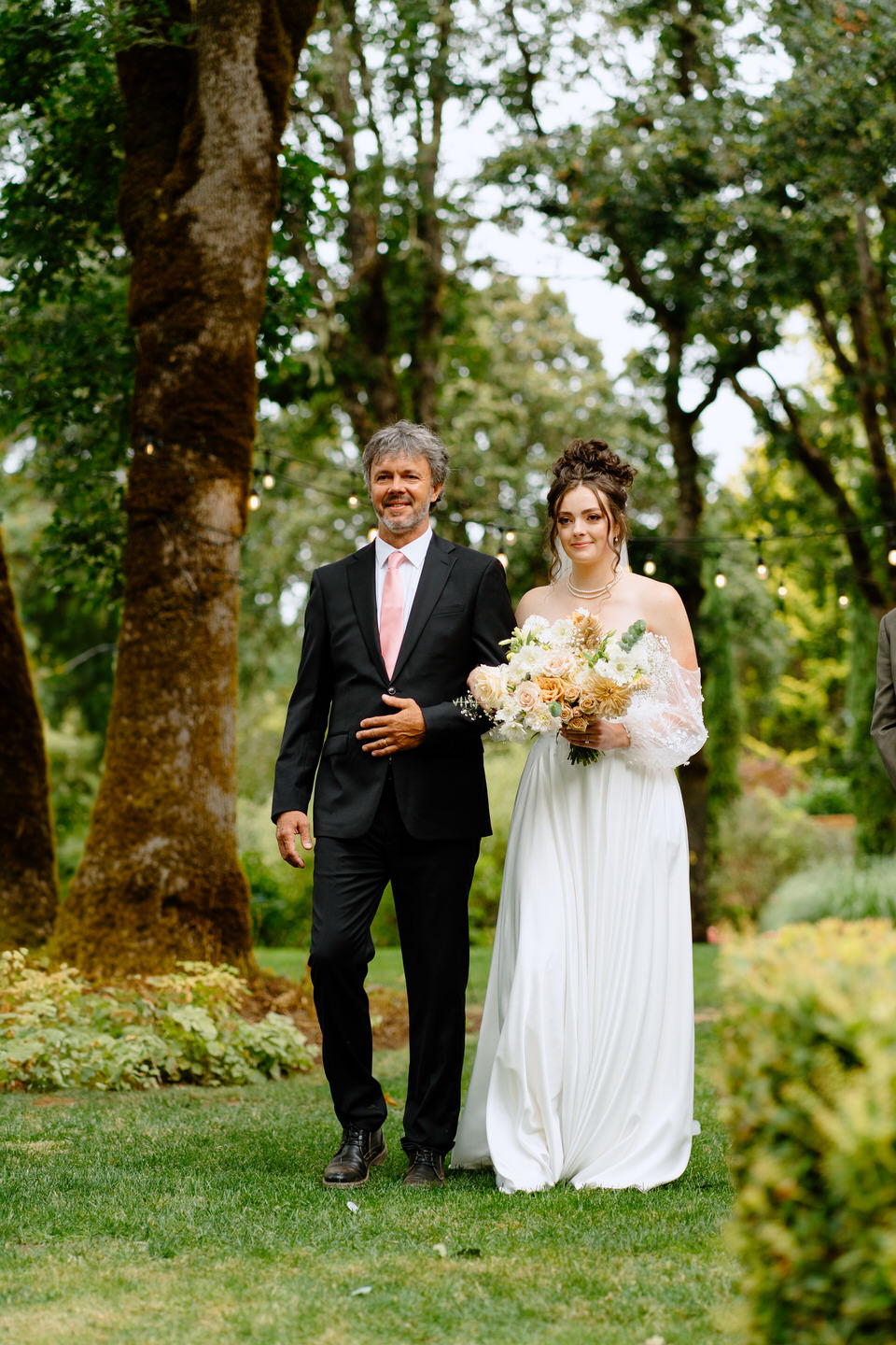 Bride and her father walk down the aisle at Navarra Gardens for the outdoor wedding ceremony in the garden.