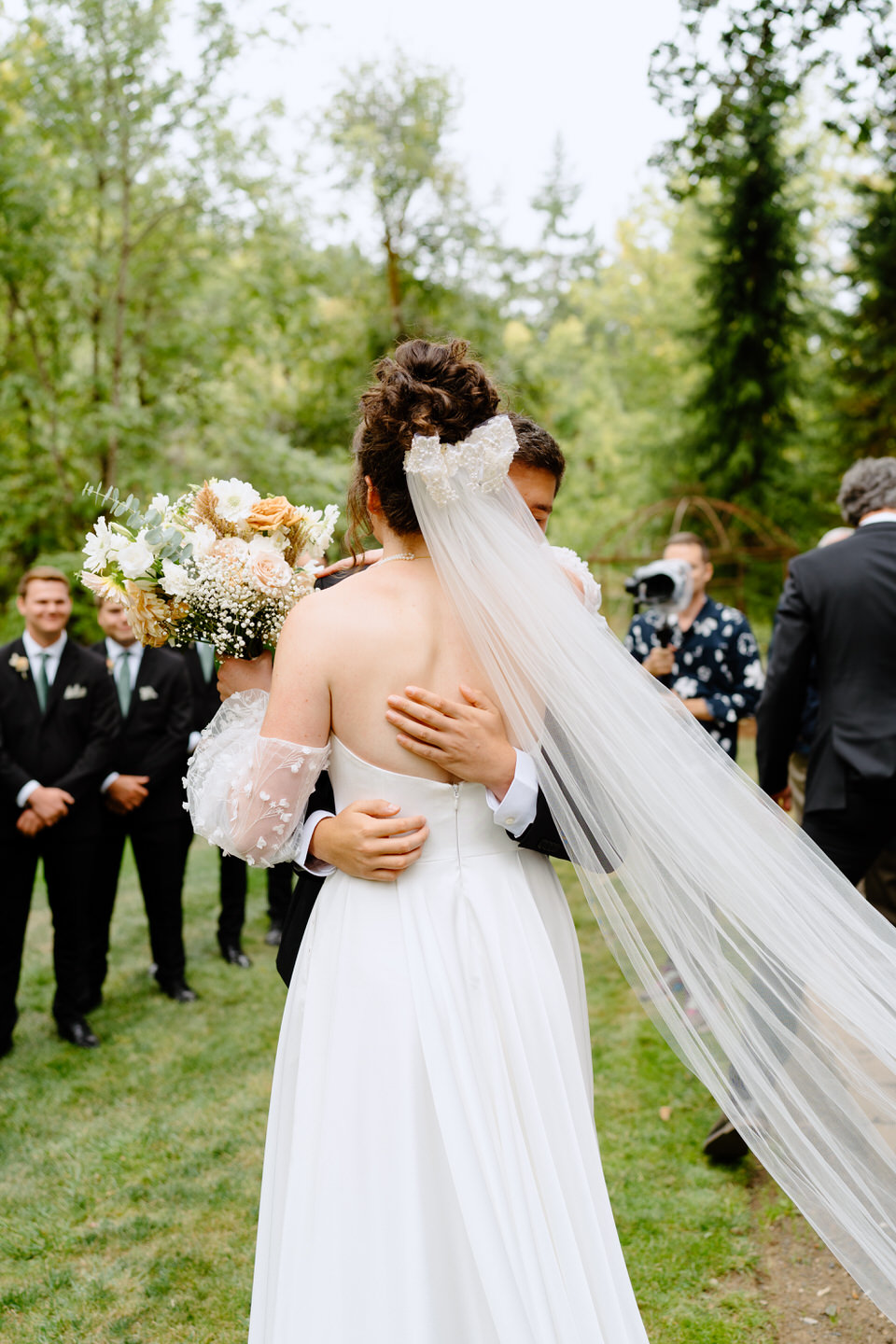 Bride and groom hug at the front of the aisle on wedding day at Navarra Gardens.