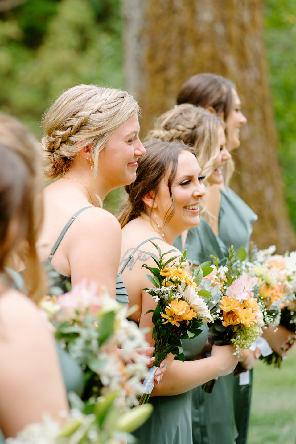 Bridesmaids smiling as they listen to vows during the wedding ceremony.