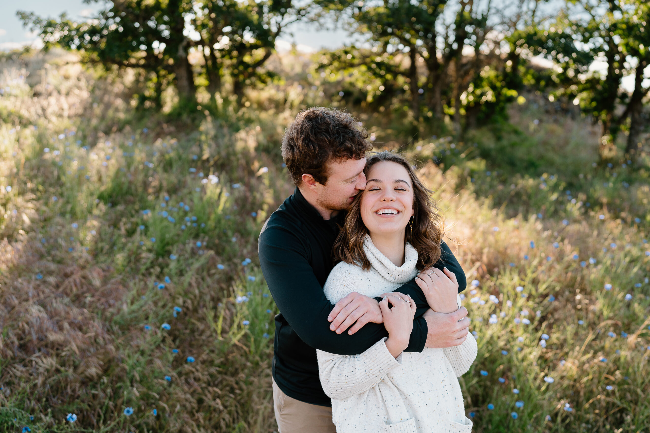 Couple wraps arms around each other in wildflowers at Rowena Crest.