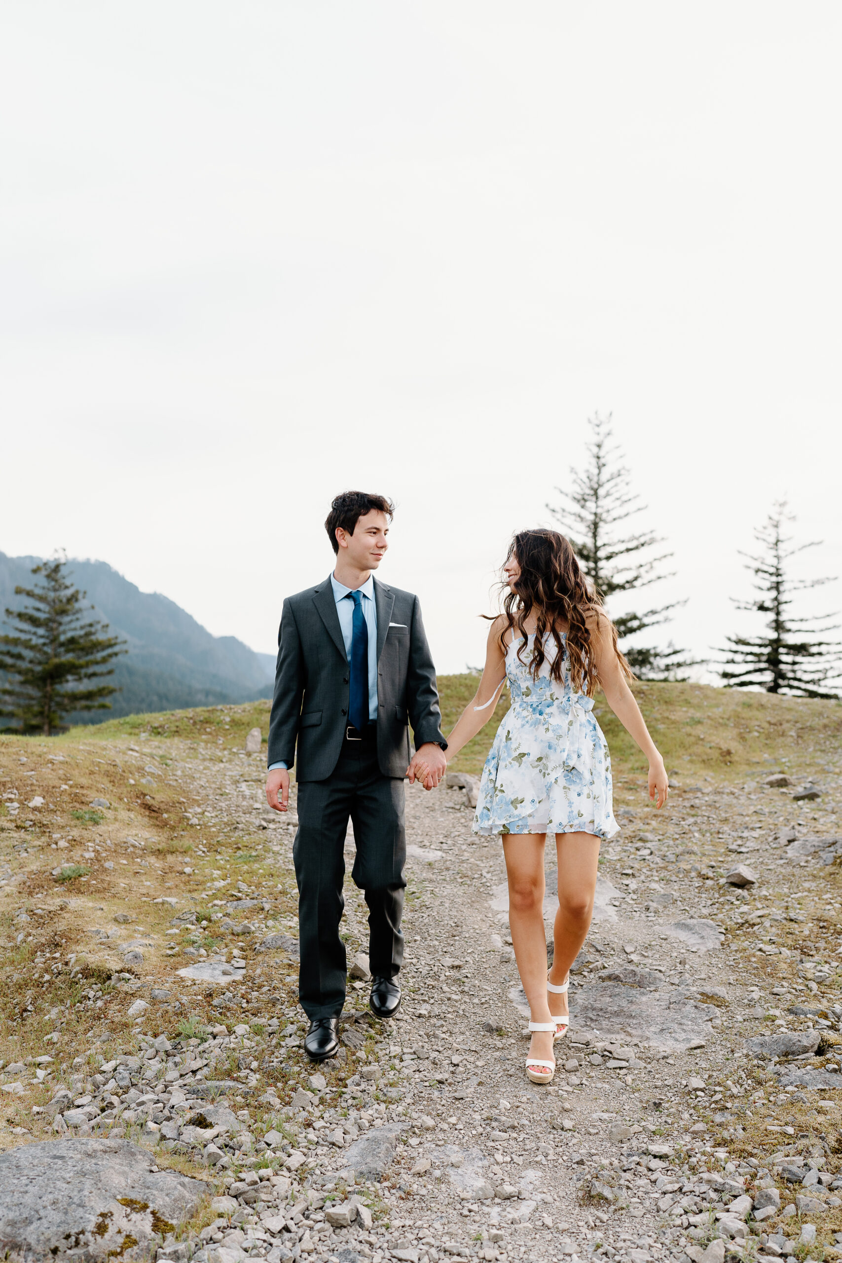 Couple holding hands and walking on rocky terrain for Oregon engagement photos.