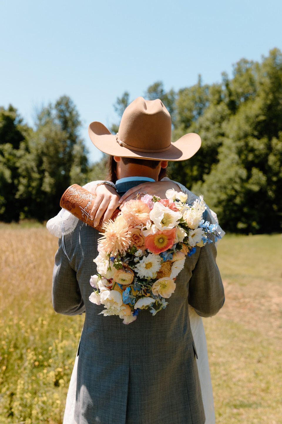 Bride hangs her bouquet over groom's shoulder