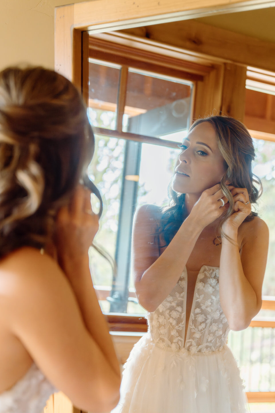 Bride putting in her earrings as she gets ready for her wedding.