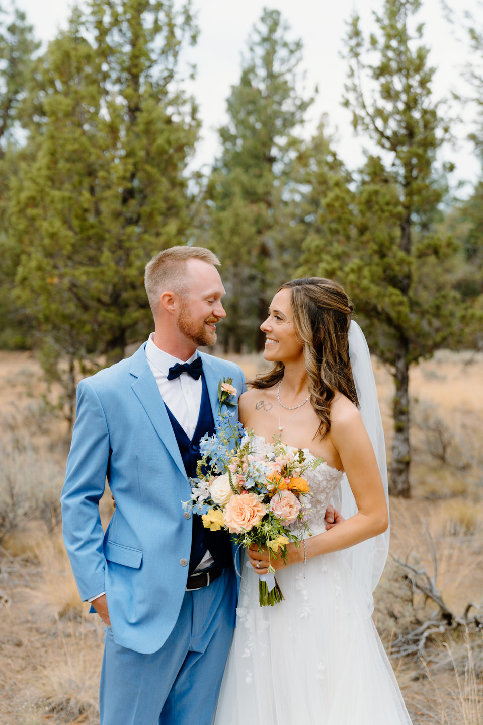 Bride and groom with wildflower bouquet and blue suit.