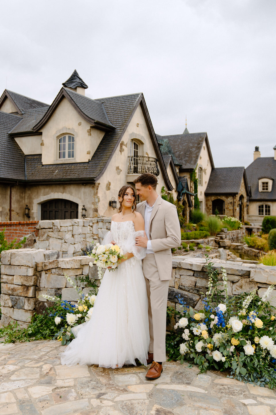 Bride and groom on bridge in front of chateau wedding venue