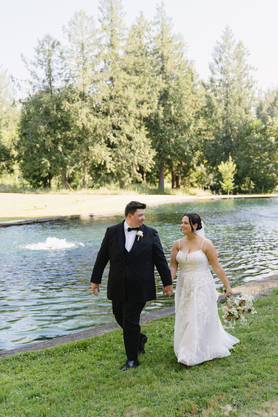 Bride and groom holding hands during Springwater Lakes Estate water