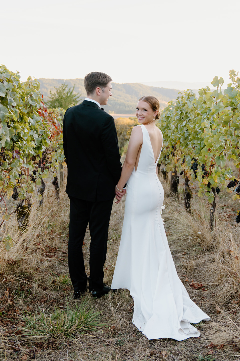 Bride and groom walk through the vineyard at Youngberg Hill for their wedding