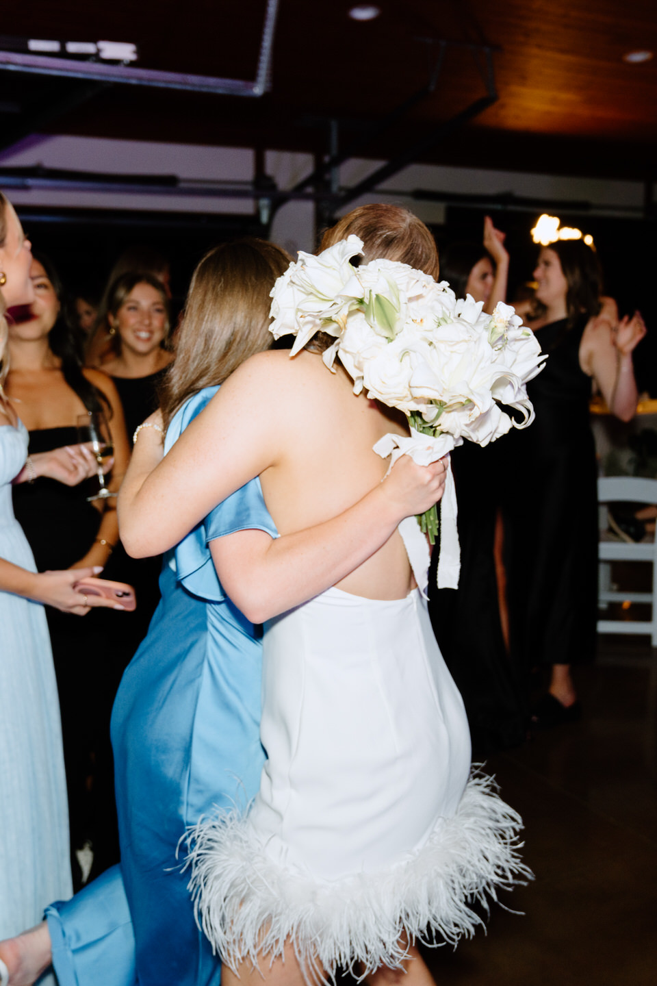 Bride and friends hug on the dance floor at wedding