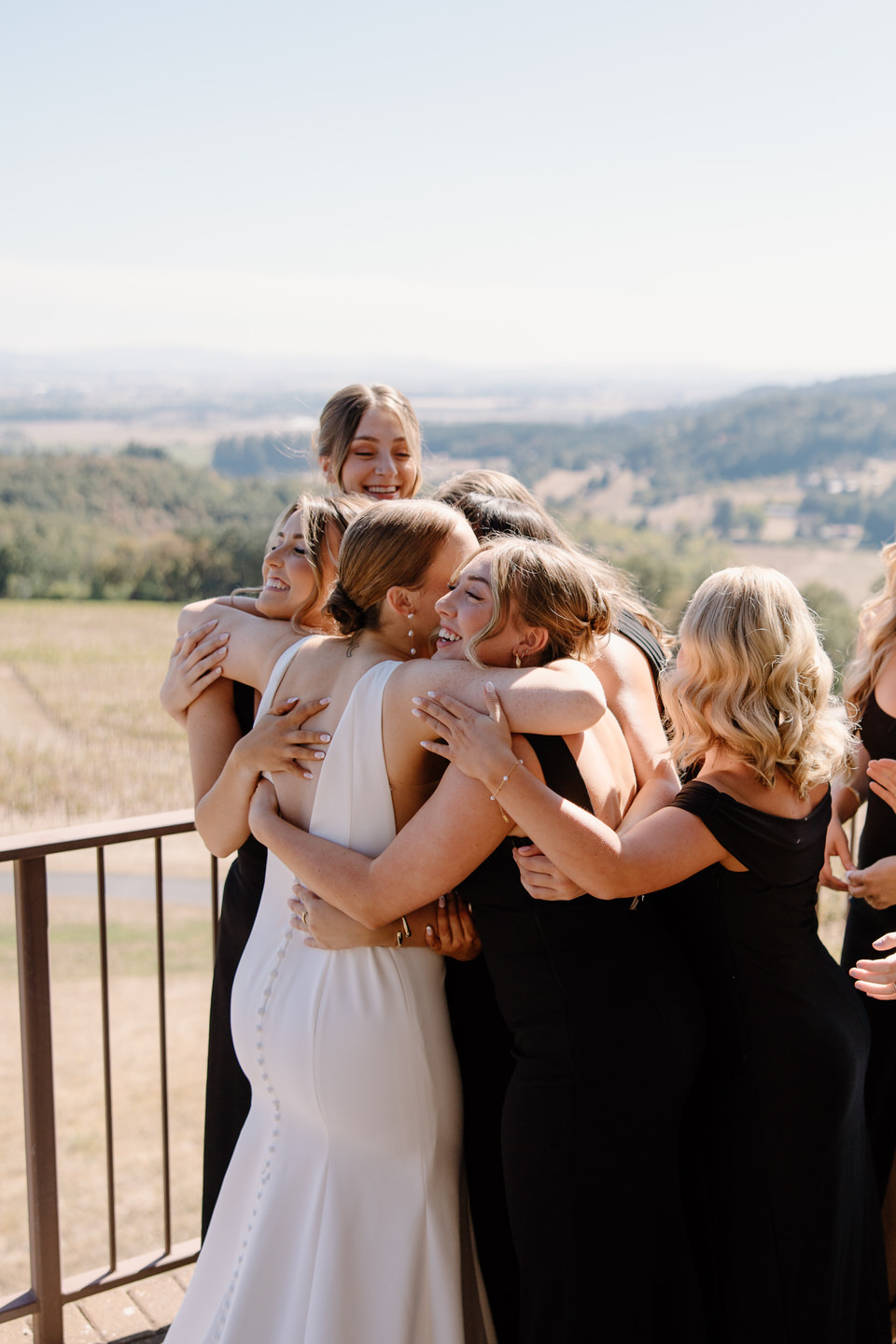 Bride and bridesmaids hugging before wedding ceremony at Youngberg Hill in Oregon.