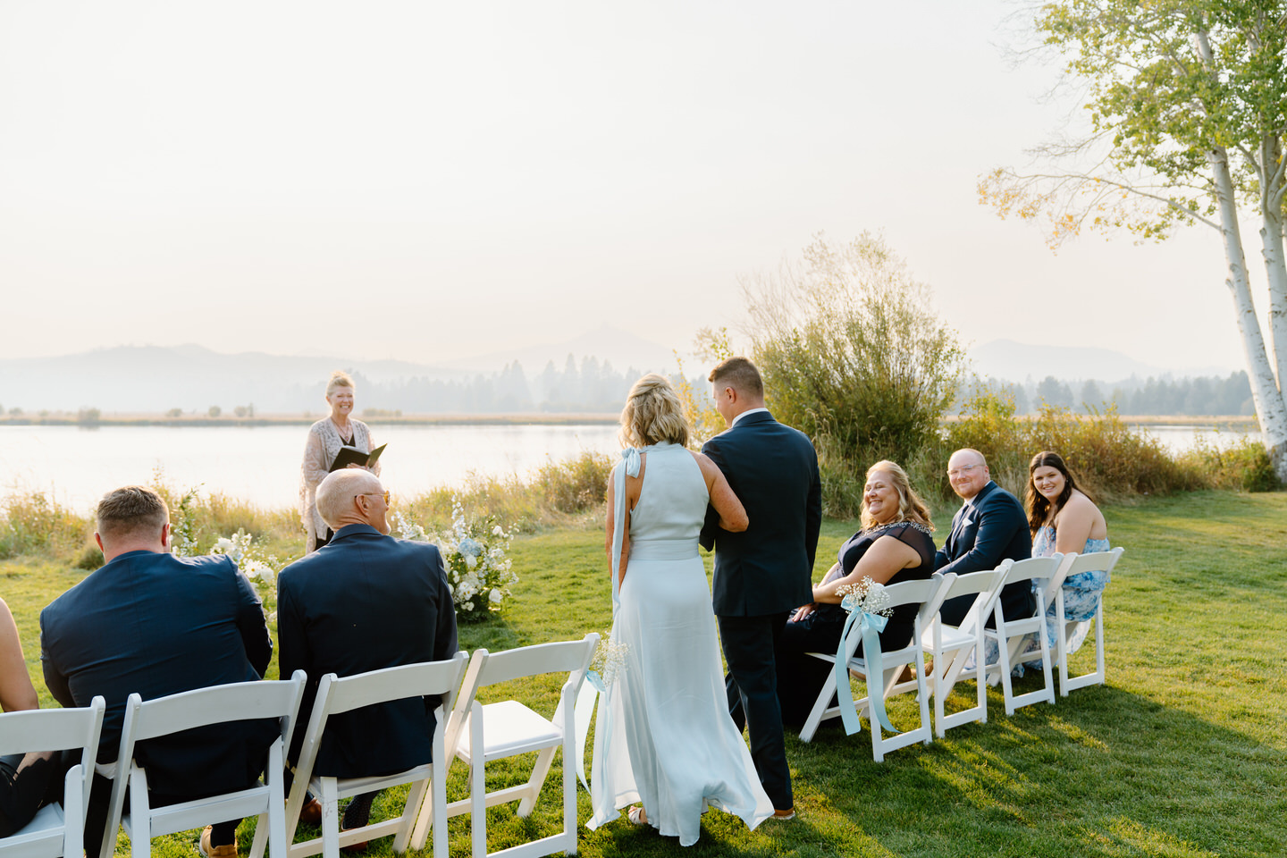 The groom and his mother make their way to the front of the aisle in front of the lake at Black Butte Ranch.