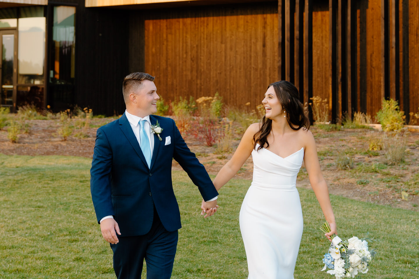 Bride and groom walk hand in hand during sunset at their Black Butte Ranch wedding, surrounded by the lodge's modern architecture.