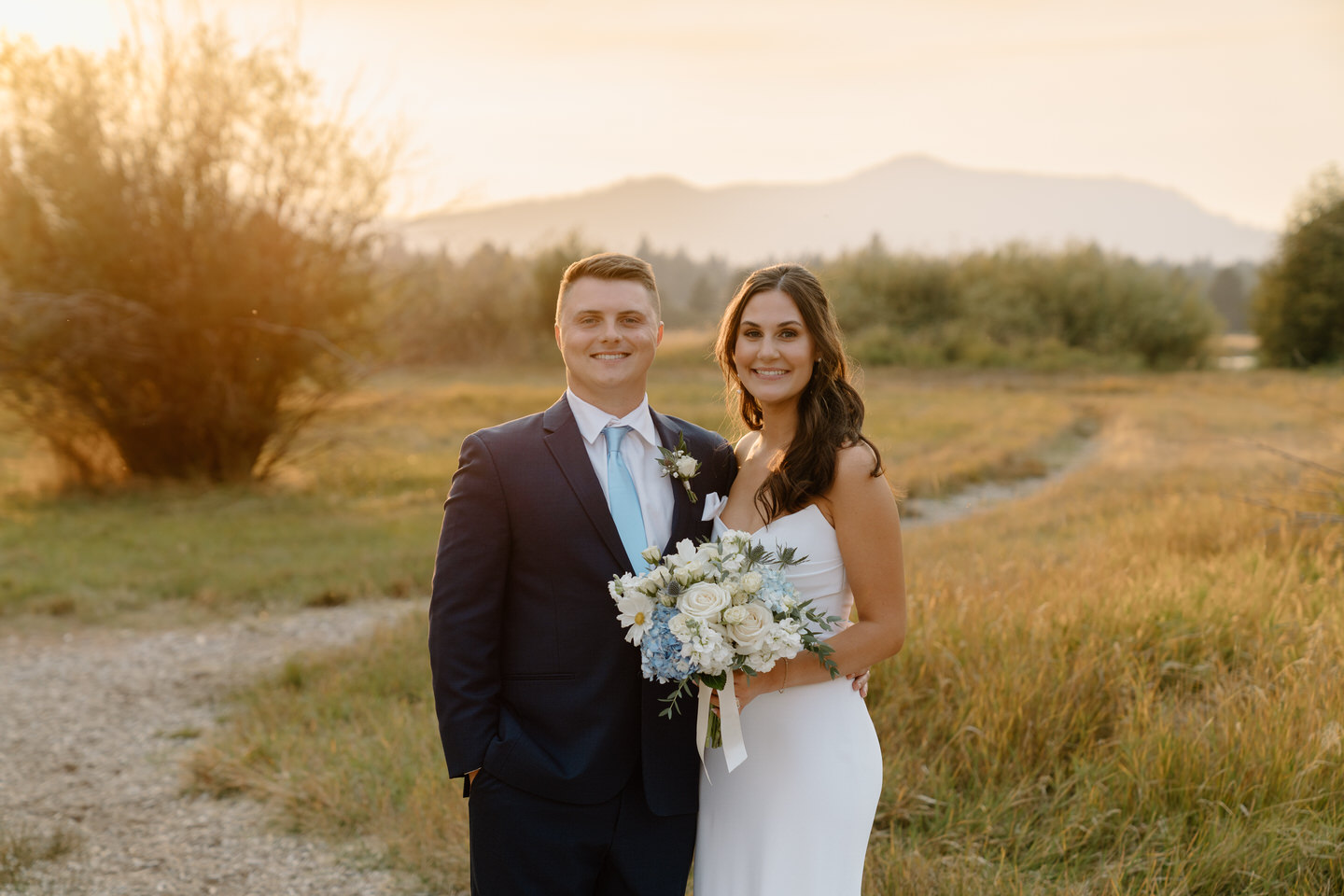 Bride and groom pose at sunset, their love glowing as brightly as the golden horizon behind them.