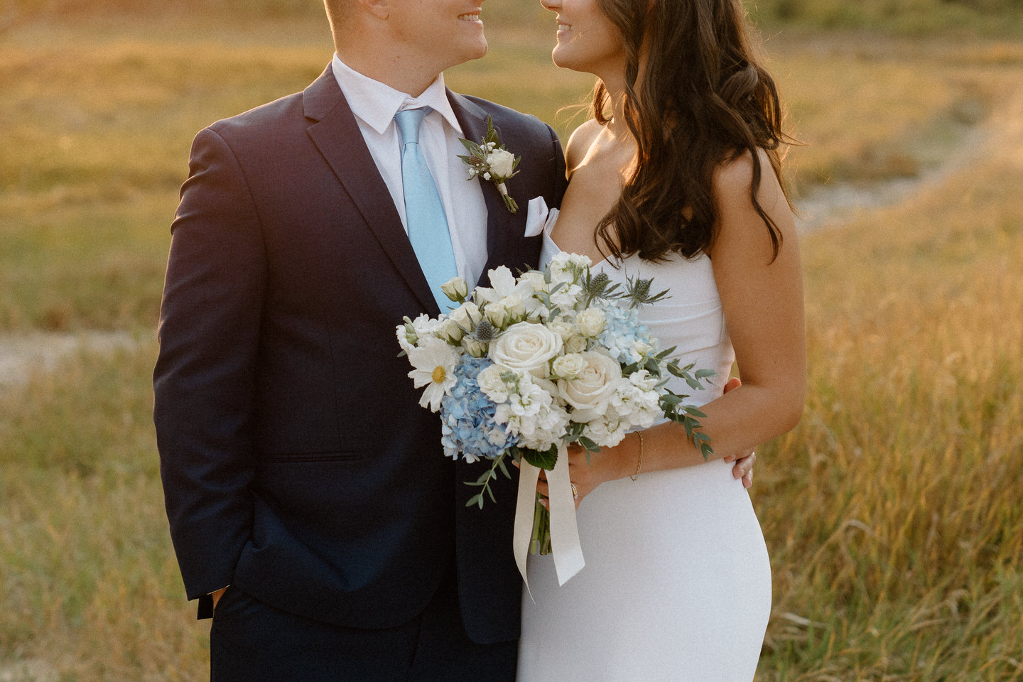 Blue and white wedding details including a groom's navy blue suit and light blue tie with Hydrangeas in bride's bouquet.