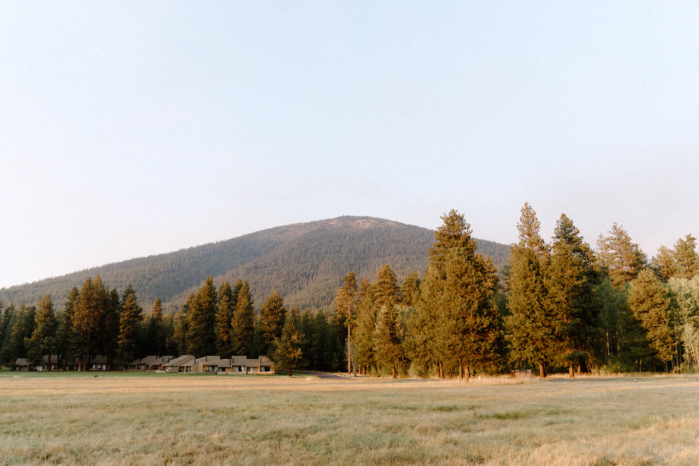 Golden hour casts a smokey orange light of Black Butte behind the Central Oregon trees.