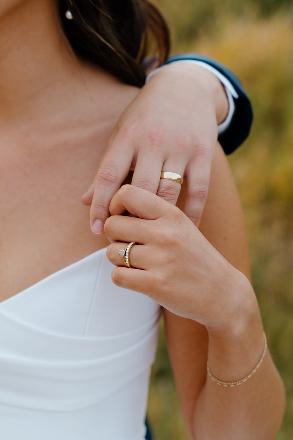 Bride and groom hold hands at sunset, their figures outlined by the warm glow of the horizon.