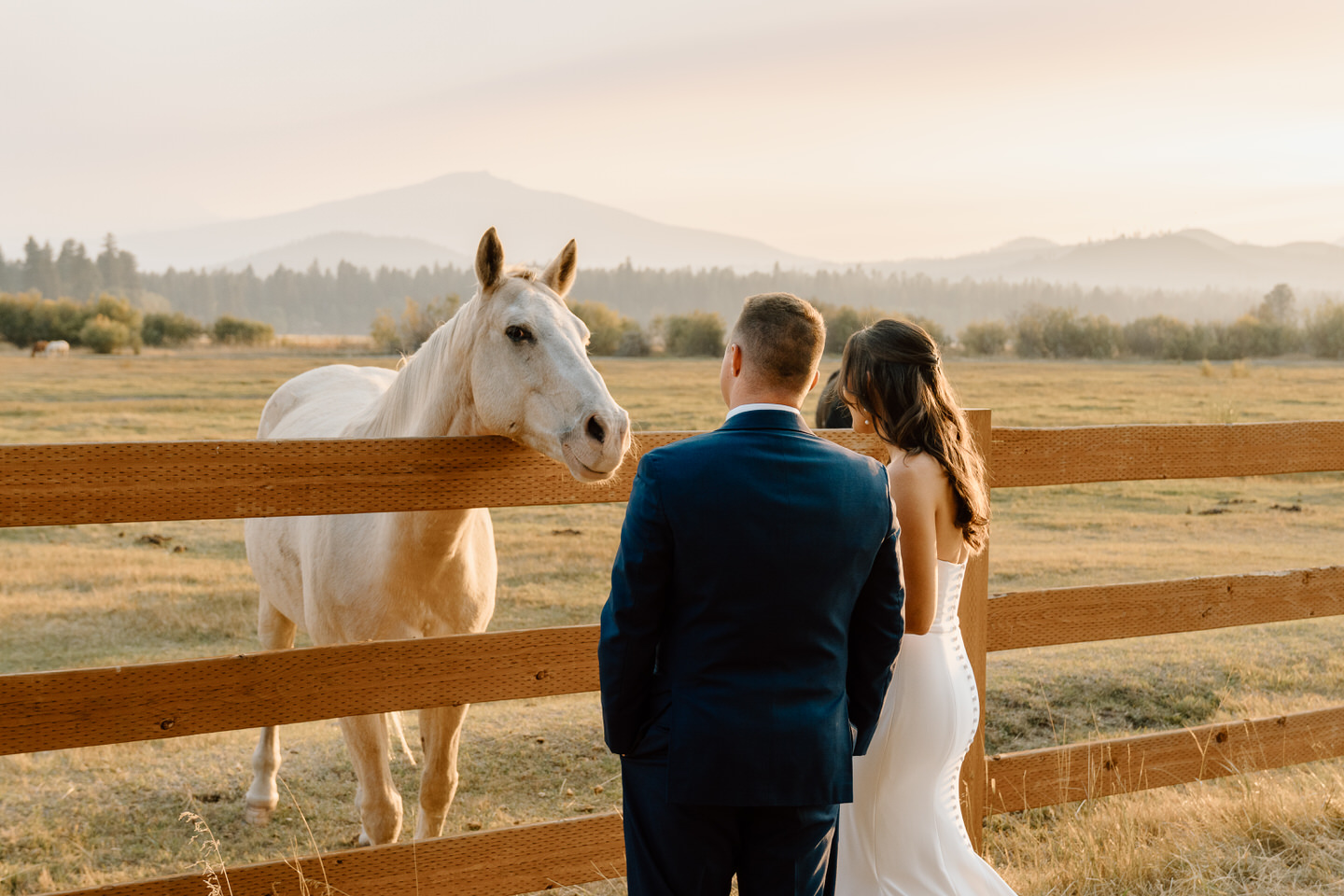 Sunset casts a golden glow on a bride and groom at Black Butte Ranch, with Central Oregon’s mountains in the background.