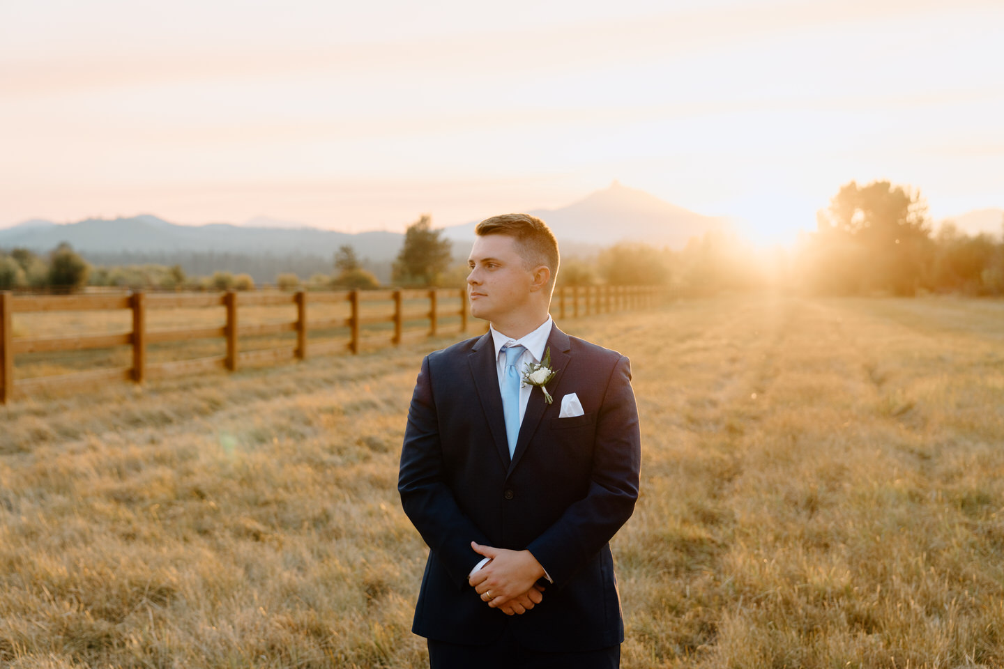 Groom in a sharp blue suit stands confidently at his Black Butte Ranch wedding, surrounded by Central Oregon’s scenic beauty.