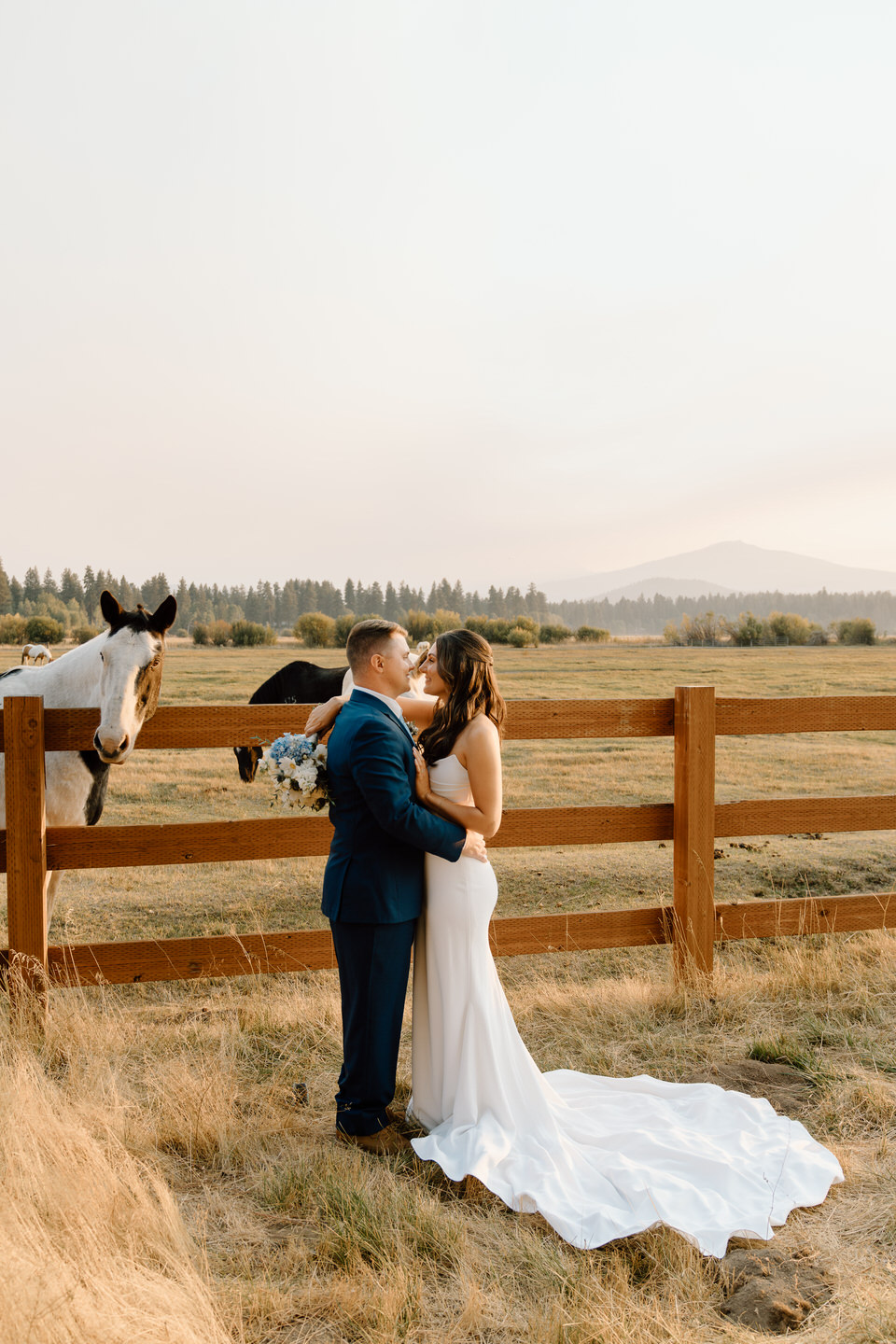 A bride and groom stand together at sunset, the golden light casting a romantic glow on their silhouettes.