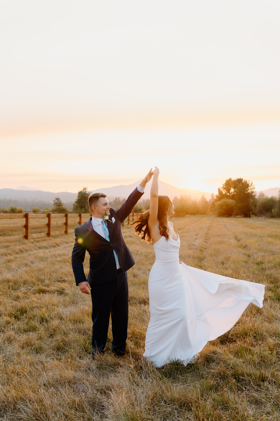 Sunset highlights the bride and groom as they share a tender moment, framed by the vibrant hues of the sky.