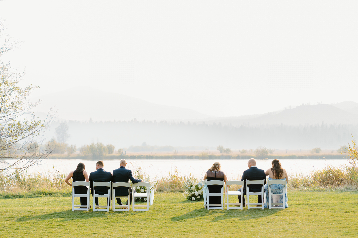 Guests sit on white chairs at Black Butte Ranch, surrounded by Central Oregon’s beauty, awaiting the bride and groom’s arrival.