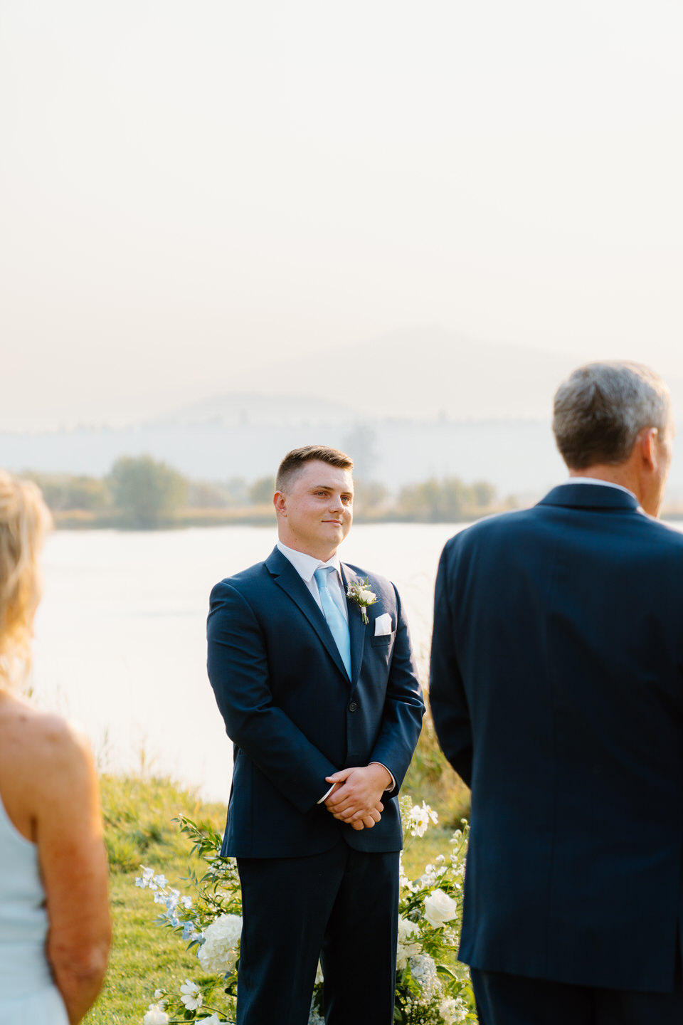 Groom beaming as he sees his bride walk down the grass aisle of their Black Butte Ranch wedding.