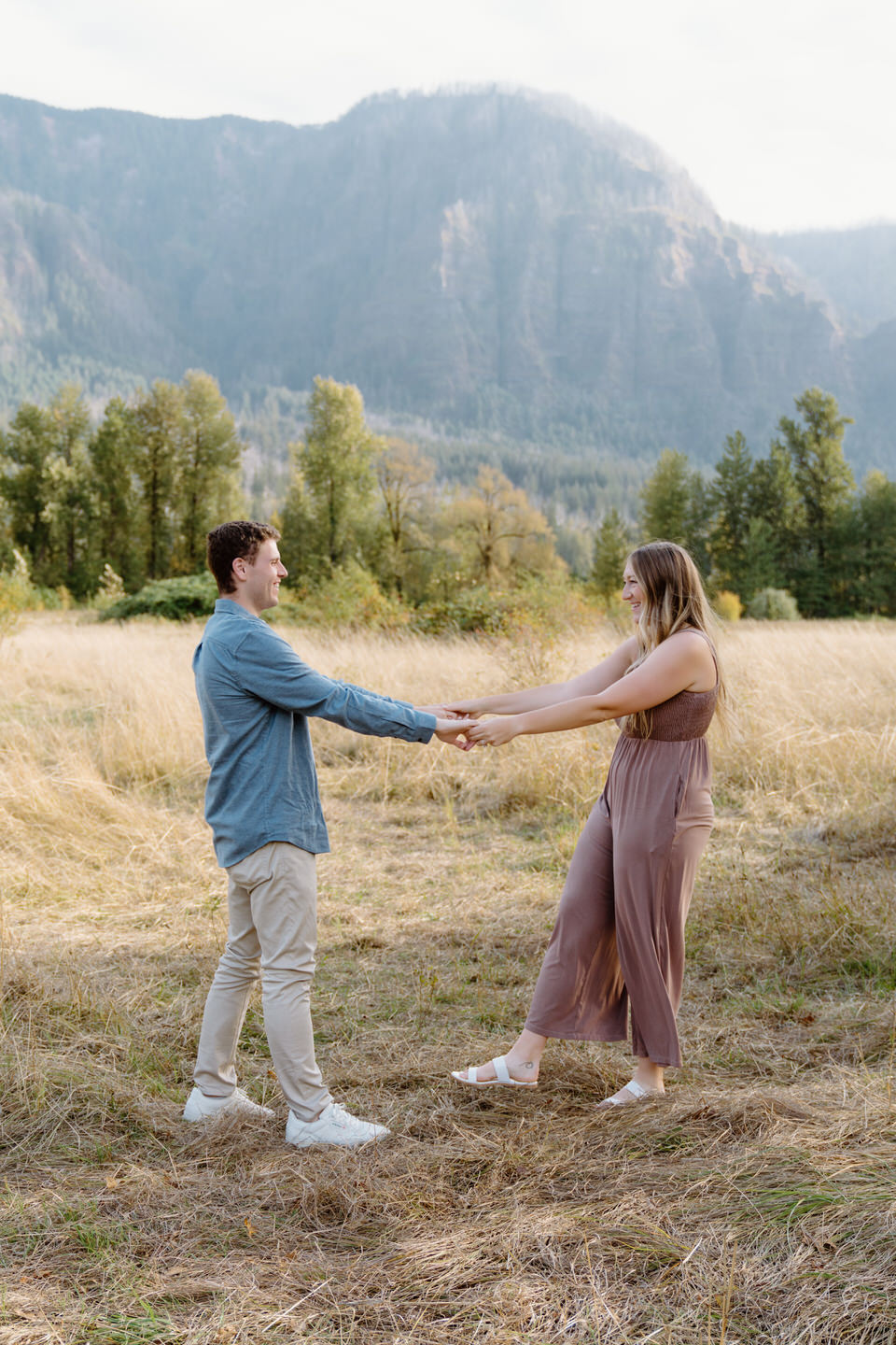 Couple standing together in the stunning Columbia Gorge, surrounded by lush greenery and golden fields, radiating joy and love during their engagement photo session.