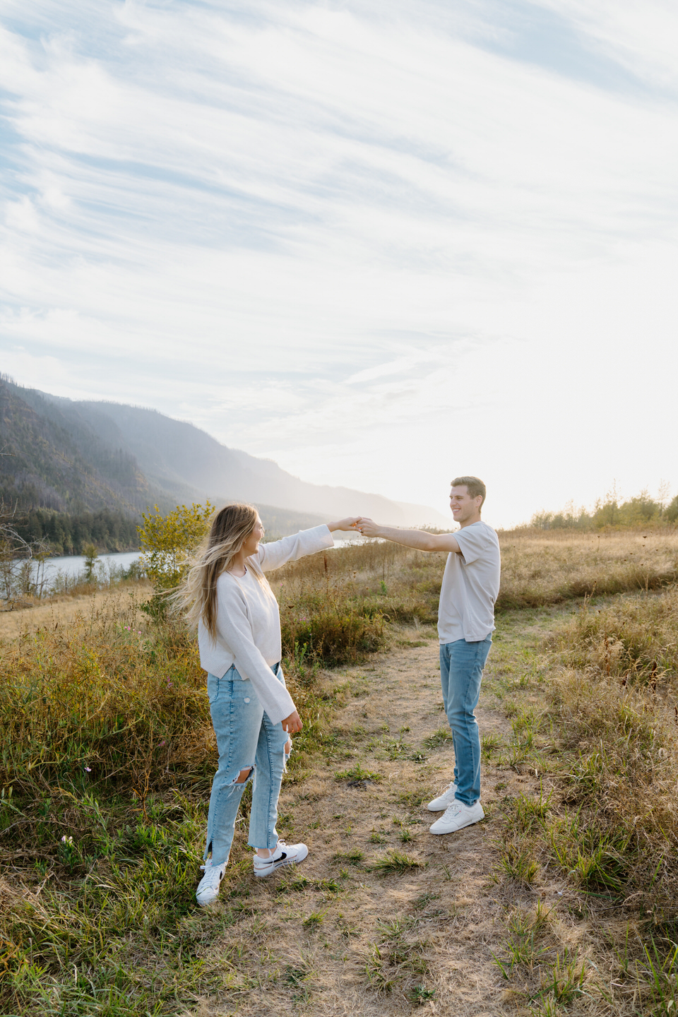 Couple dancing playfully in the Columbia Gorge during their Oregon engagement photos, surrounded by vibrant greenery and golden summer sunlight.