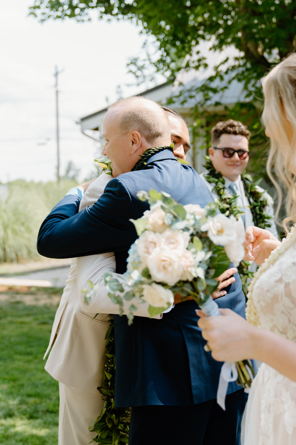 Bride's father and groom hug at the front of the aisle for Oregon wedding ceremony.